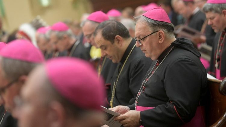 Obispo y sacerdotes en oración junto al Papa.