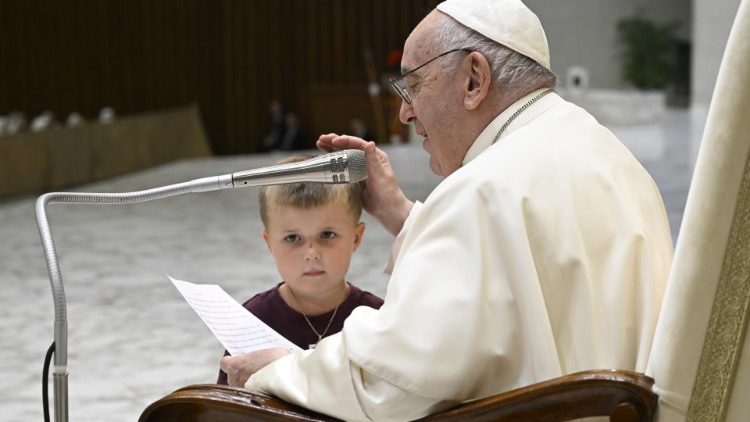 A little boy runs up to Pope Francis during General Audience