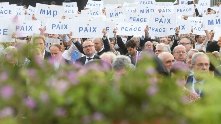 La platea solleva cartelloni con la scritta "Pace"