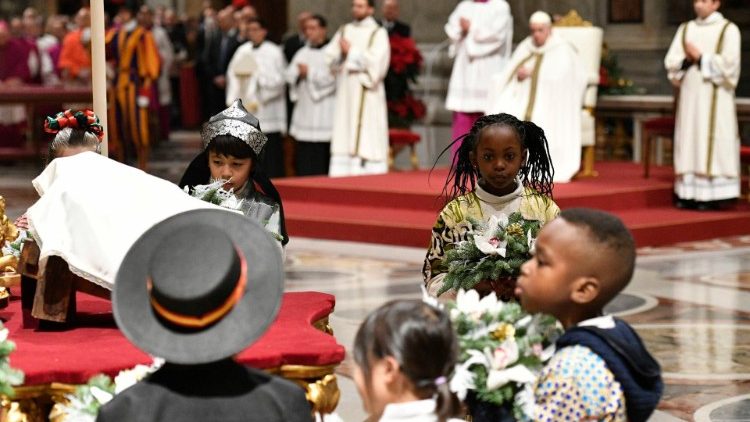Un grupo de niños presenta una ofrenda floral a los pies del Niño Dios.