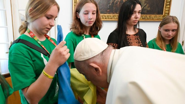 Pope Francis kisses the Ukrainian flag at a meeting with young Ukrainian pilgrims in Lisbon