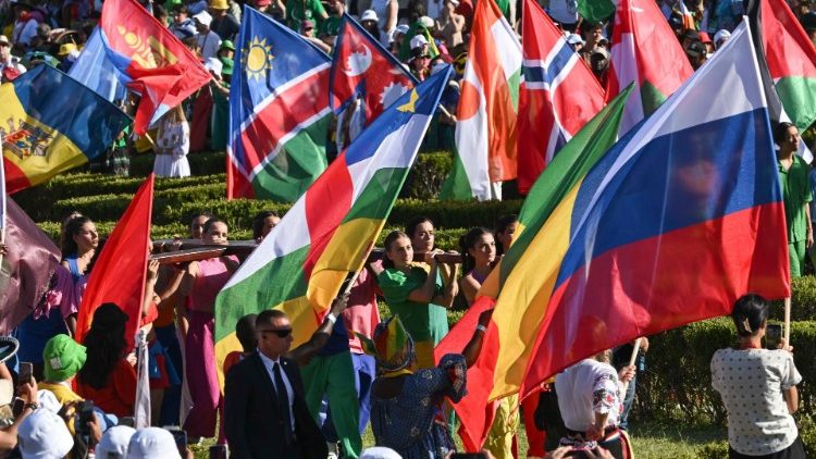 The World Youth Day Pilgrim Cross is carried in the midst of the parade of flags