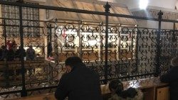 Fedeli pregano accanto alla salma di San Pio OKOKO.jpg
