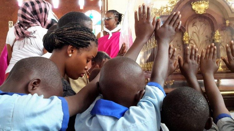 Fiéis de Burundi tocam relíquia de Santa Teresa que peregrinou pelo país em 2018.