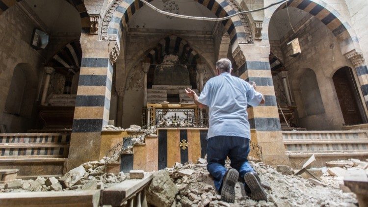 A man prays in a destroyed church