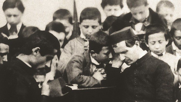 A photo of Don Bosco (R) with young people.  