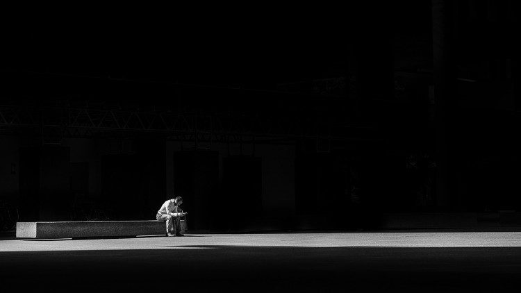 A man sits alone in darkness