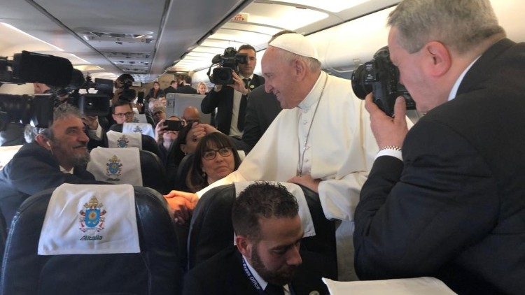 Le Pape François salue des journalistes à bord de l'avion lors d'un voyage apostolique.