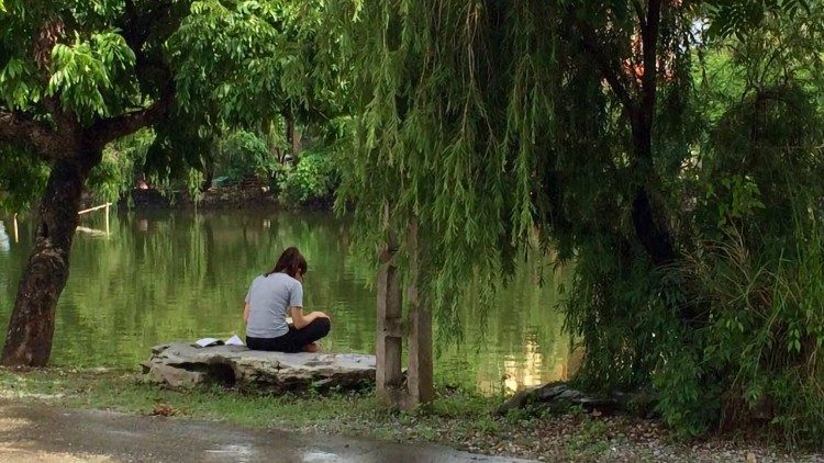 A Catholic student prays in a scenic, lakefront setting