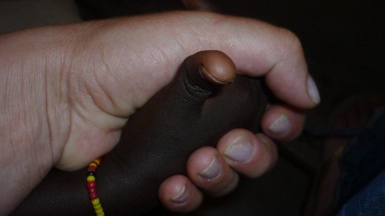 Una missionaria stringe la mano di un bambino
