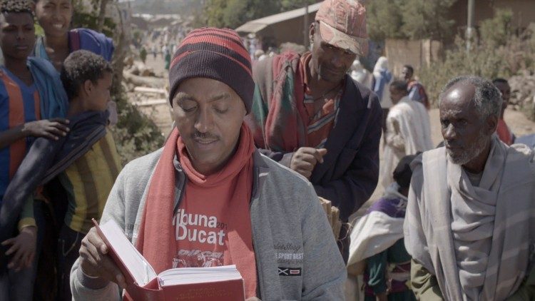 In un mercato etiope l'interprete Behranu Tesfaye legge un passo del Catechismo
