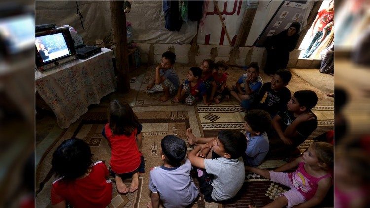 Displaced children watch SAT-7 satellite TV in a tent in a refugee camp 