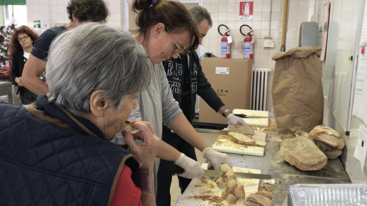 Volontarie tagliano il pane nella cucina di Rebibbia