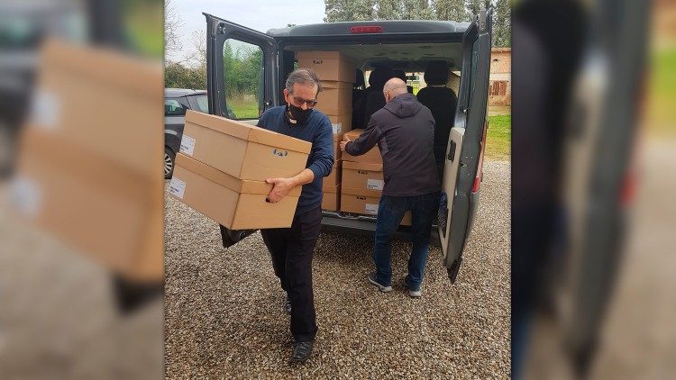 Il cardinale Paolo Lojudice aiuta a scaricare il materiale donato dal Papa