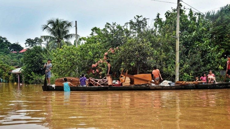 Pobladores indígenas atravesando el río en Puerto Maldonado, Perù