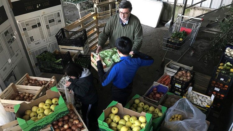 Don Luigi e i suoi collaboratori mettono anche verdura fresca nel carrello per la famiglia in difficoltà