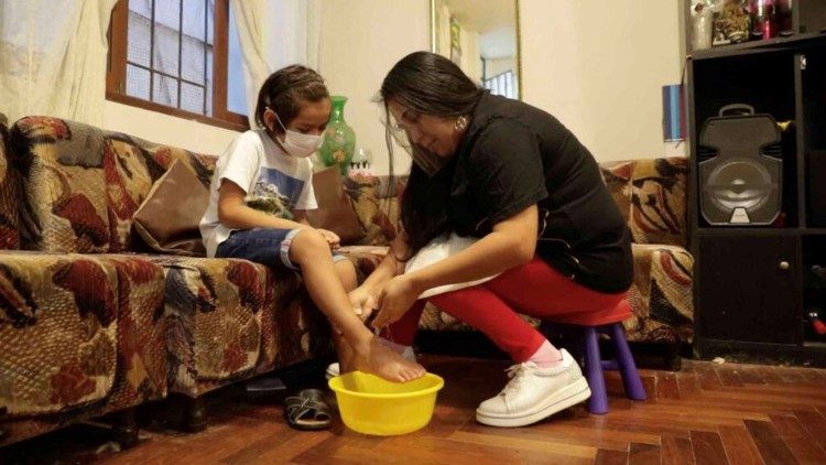 Una mujer lava los pies a su hija