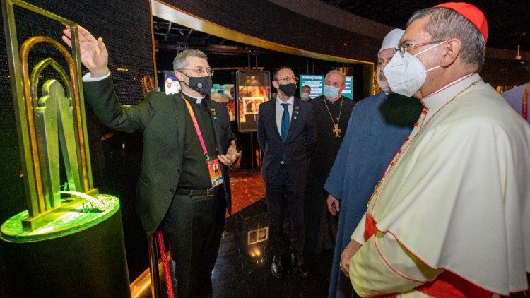 Monsignor Trafny (a sinistra) guida i membri dell'Alto Comitato per la Fratellanza Umana nella visita al padiglione della Santa Sete ad Expo Dubai. A destra, il cardinale Ayuso, presidente del Comitato