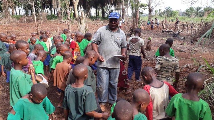 Os pigmeus e o padre Pierre Latevi na missão na região de Mungbere, RDCongo