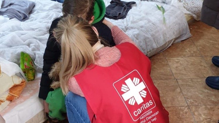 A caritas volunteer comforts a young Ukrainian refugee