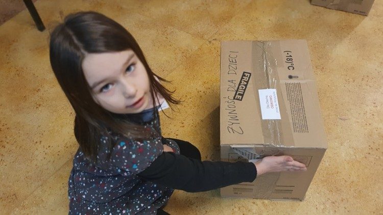 A Varsavia una bambina polacca prepara un pacco per l'Ucraina