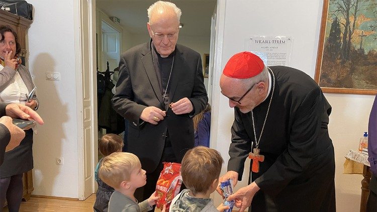 Duas crianças oferecem biscoitos ao cardeal