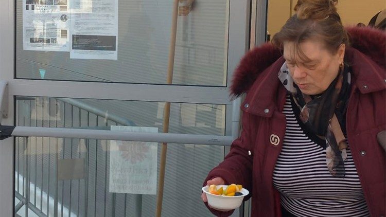 A Ukrainian woman holds her bowl of soup offered by Caritas Krakow