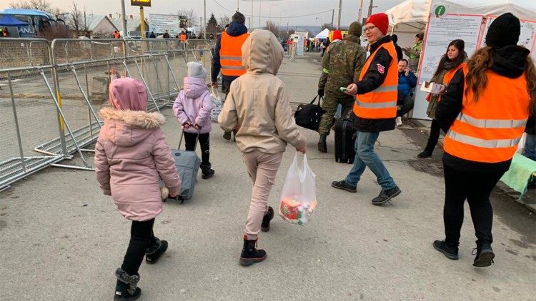 Niños ucranianos llegan con pequeñas mochilas y bolsas a la frontera con Eslovaquia
