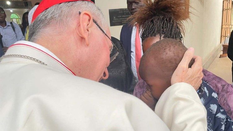 El cardenal Parolin acaricia al bebé Nelson, que necesita una operación urgente en Jartum.