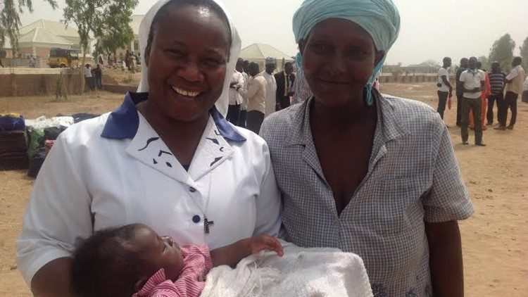 La Hna. Anne Falola, OLA, con una madre y un niño en el campo de los desplazados internos de Abuja, en Nigeria, en 2016.