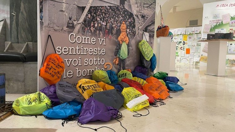 L'installazione con gli zainetti e la grande foto del punte crollato di Irpin, in Ucraina