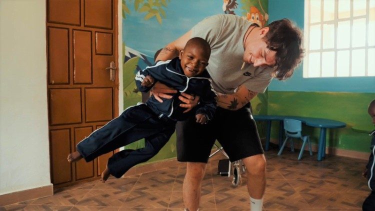 Un volontario gioca con un bambino disabile della missione di Laare, Kenya