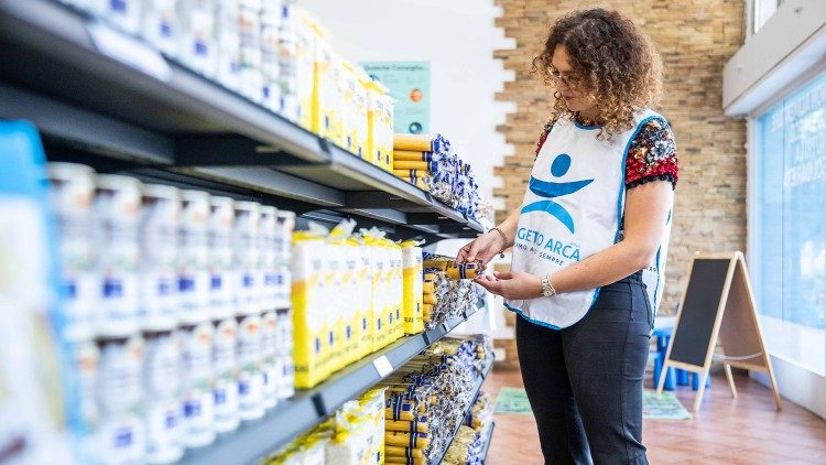 Una volontaria di Progetto Arca ordina generi di prima necessità negli scaffali  del nuovo Market solidale di Rozzano