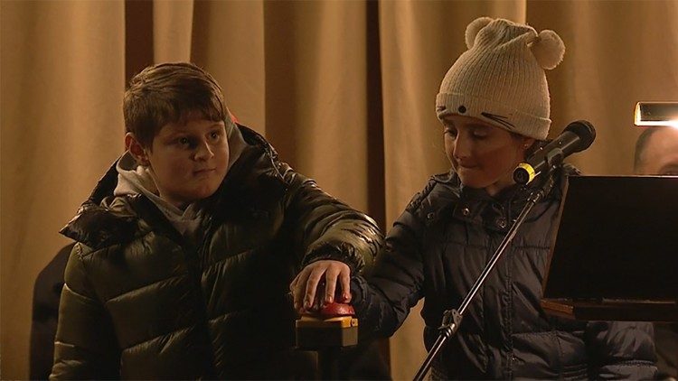 Due bambini accendono l'albero